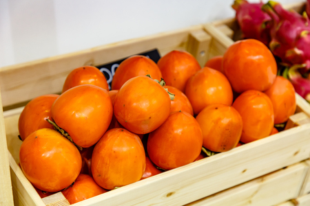 Persimmon lies in a wooden box in the store.の写真素材