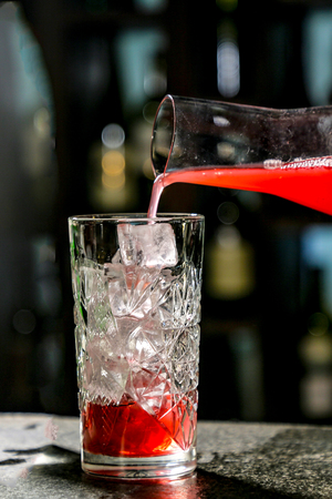 The bartender pours red juice or juice into a cocktail glass Cape Cod or Cape Codderの写真素材