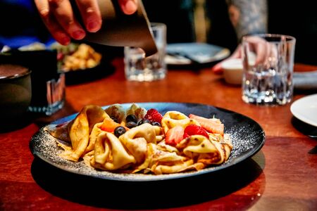 Pancakes with berries (blueberries and strawberries) are poured with caramel sauce.の写真素材