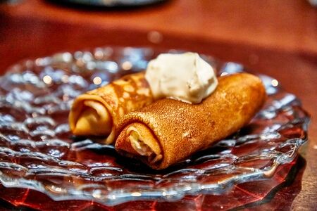 Pancakes rolled into a roll with sour cream lie on a plateの写真素材