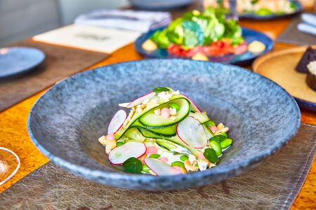 Salad of cucumbers, radishes, peas is in the plateの写真素材