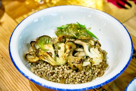 Buckwheat porridge with mushrooms oyster mushrooms lie in a plateの写真素材