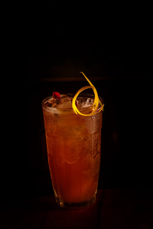 Red cocktail with ice, decorated with rose buds, standing on the bar
