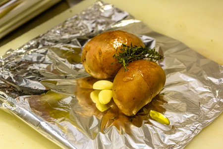 Potatoes with garlic, oil and thyme are prepared for baking in foilの写真素材
