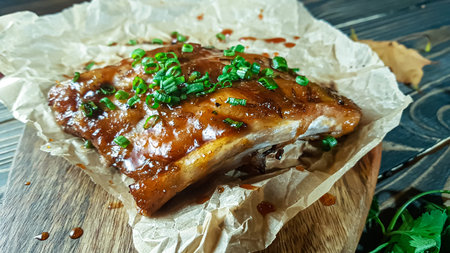 Pork ribs with green onions baked with sauce lie on a wooden Board