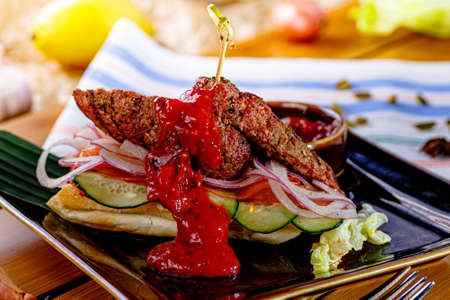 Kebab with vegetables and tomato sauce on bread is on the plateの写真素材