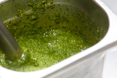 Recipe for pesto sauce. Basil leaves with olive oil are whipped in a blender.