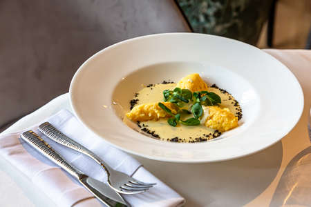 Polenta with cheese sauce is on a plate on the table in a restaurantの写真素材