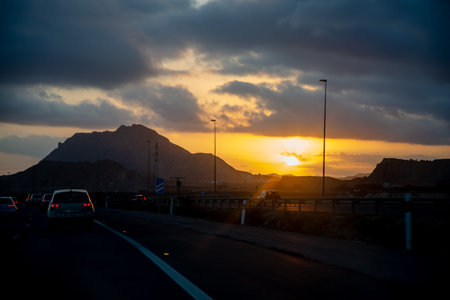 Evening, the sun sets behind the mountain, the view from the car window on the road