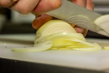 Chef cutting the onion on a wooden boardの写真素材