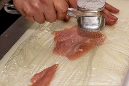 Cook beating a chicken breast with a hammer, close-up.の写真素材
