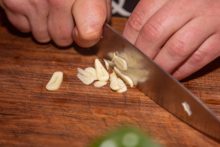 Chef slicing garlic on the cutting board with a knife.の写真素材