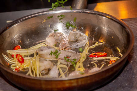 Black Tiger Shrimps Roasted with herbs. Grilled fresh shrimps on gas stove being fried in pan with butter or oil. Frying raw prawns. Concept of cooking shrimps with spices. close-up macroの写真素材