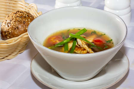 Chicken soup with vegetables in white bowl. Gray stone background. close up.の写真素材