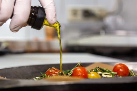 food concept. Chef is pouring olive oil over fresh salad in restaurant kitchen.の写真素材