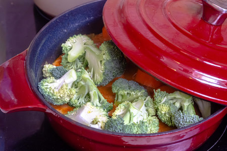 Delicious Homemade Chicken Stew with Green Pea, Broccoli and Bell Pepper in Black Saucepan isolated...