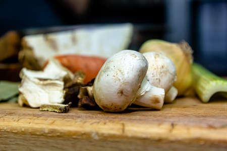 Raw champignons on a plate and olive oil jar on a white wooden table. Cooking fresh button mushrooms Agaricus bisporus. Concept of vegetarian food ingredient rich in vegetable protein. front view.の写真素材