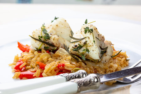 Fish dish - fried cod fillet with boiled white rice and fresh fruit salsa on white table.