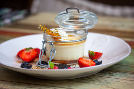 sweet dessert with fresh berries and honey in a glass jar on a wooden tableの写真素材