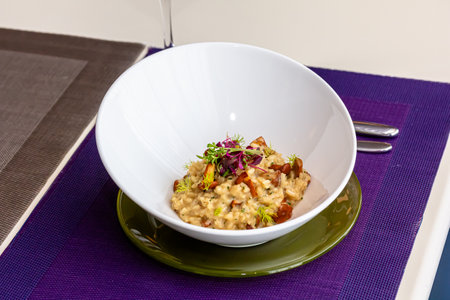 Risotto with mushrooms in a white bowl on a table.の写真素材