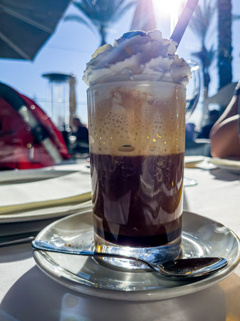 Iced coffee with whipped cream in a glass on the table.