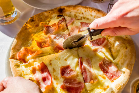 Pizza with ham and cheese on a plate in a restaurant.の写真素材