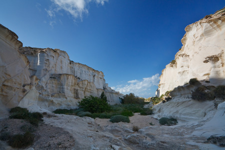Water carved canyon with some shrubby vegetation on the coast of Milos island, Greece.の写真素材
