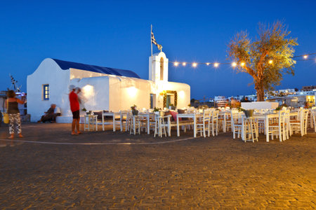 Tables of a restaurant in front of a church in the harbour of Naousa village on Paros island, Greeceのeditorial素材