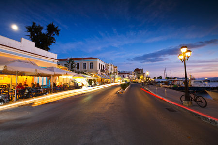 View of the seafront with coffee shops, bars and restaurants and fishing boats in the harbour of Aegina island, Greeceのeditorial素材