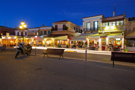 Street view of the coffee shops, bars and restaurants at the seafront of Aegina town, Greeceのeditorial素材