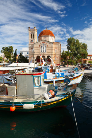 View of Ekklisia Isodia Theotokou church and fishing boats  in the harbour of Aegina island, Greeceのeditorial素材