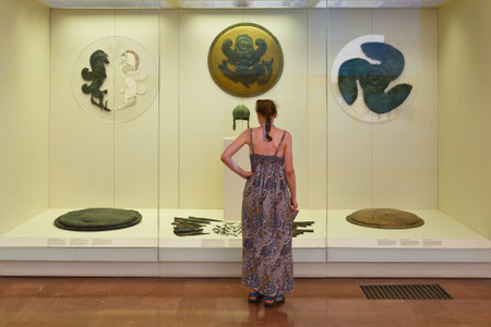 Visitor looking at shields in the Archaeological museum of Olympia.のeditorial素材