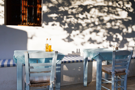 Restaurant tables under a tree with small bottles of olive oil.の写真素材