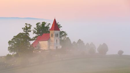 Rural Gothic church in a cemetery on a foggy morning.の写真素材