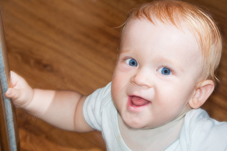 Little baby boy with blue eyes in mirror reflectionの写真素材