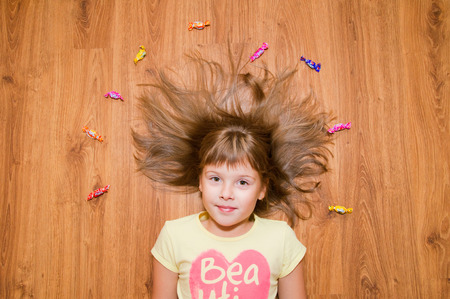 Younger girl on the floor nice smiles and candyの写真素材