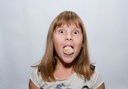Young Girl with sushi in mouthの写真素材