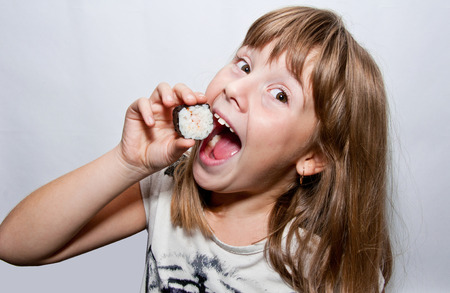 Young girl eats sushi by handsの写真素材
