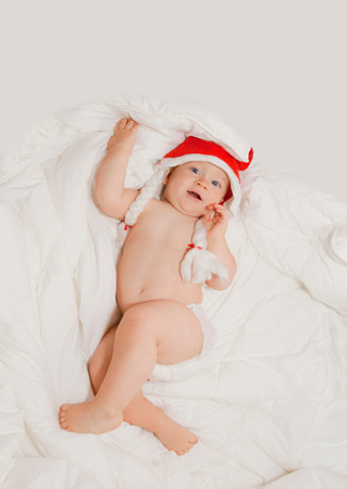 Baby boy with blue eyes in red Christmas hat liesの写真素材