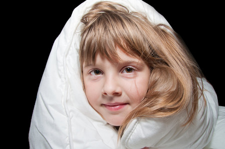 Junior girl covered withe blanket on black backgroundの写真素材