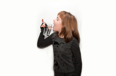 Teen girl drinks water from glass isolated whiteの写真素材