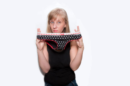 Young woman with panties with polka dots in hands isolated pose size