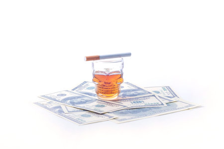 Bad unhealthy habits - addiction to ciagrette, alcohol and gambling. Money, cigarettes and glass in the form of a glass of whiskey skullの写真素材