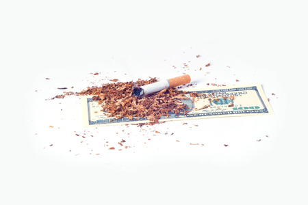 In a pack of dollar bills lying broken in and a lot of cigarette tobacco leaves aroundの写真素材