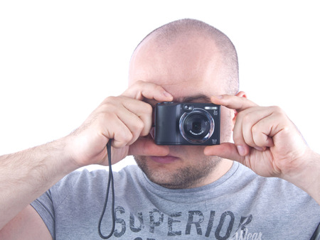 young man with small black photocamera in hands near face isolated whiteの写真素材