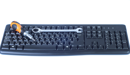 On the black keyboard is a screwdriver and wrench isolated whiteの写真素材