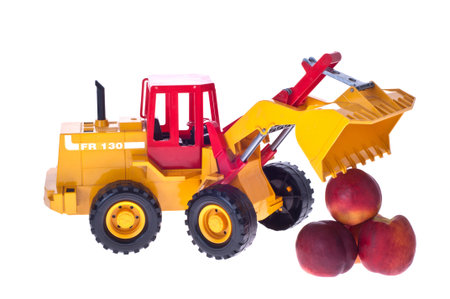 Children's toy tractor destroys a mountain of peaches isolated white