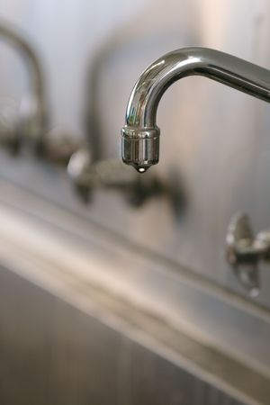 a water tap dripping leaking a drop of waterの写真素材