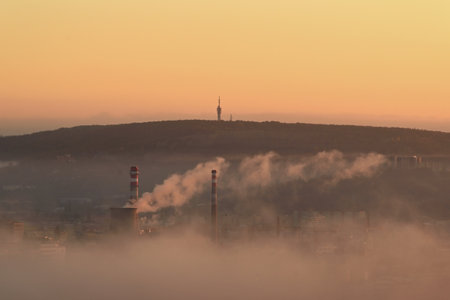 View of the city with a smoke from a heating plant in Brno, Czech Republic, on a foggy morningの写真素材