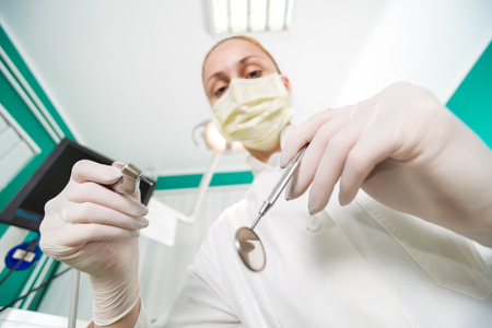 Dentist holding dental drill and Angled Mirror for inspecting a patient  Selective Focus の写真素材